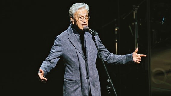 Caetano Veloso steht in einem hellen Lichtkegel auf der Bühne der Elbphilharmonie. © Daniel Dittus 