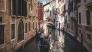 Ein venezianischer Gondoliere fährt seine Gondel durch die engen Kanäle von Venedig. © picture alliance / CHROMORANGE Foto: Michael Bihlmayer
