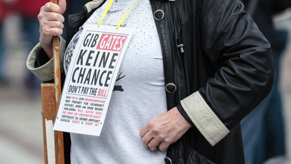 Eine Frau auf einer Demo der Initiative "Querdenken" hat ein Schuild mit der Aufschrift "Gib Gates keine Chance - don't pay the Bill" um den Hals gehängt. © picture alliance Foto: Dennis Ewert