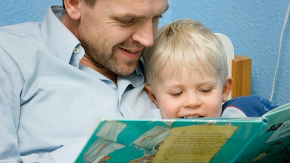Vater liest seinem kleinen Sohn aus einem Kinderbuch vor. © colourbox Foto: -