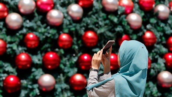 Ein Mädchen fotografiert mit Ihrem Smartphone einen Weihnachtsbaum © picture alliance / Godong Foto: Pascal Deloche