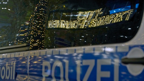 Die Lichterkette mit dem Schriftzug Weihnachtsmarkt spiegelt sich im Fenster eines Polizeiautos © picture Alliance Foto: Thomas Bartilla