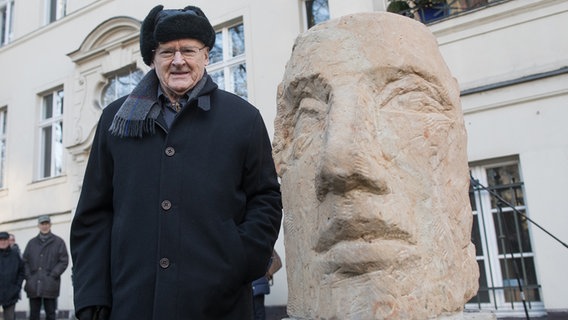 Gerhard Wolf steht neben der Skulptur "Maske der Medea" vor dem Wohnhaus von Christa Wolf in Berlin-Pankow. © picture alliance / dpa Foto: Jörg Carstensen