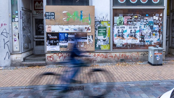 Ein Fahrradfahrer huscht an einem leeren Laden in Schwerin vorbei © picture alliance/dpa | Jens Büttner 