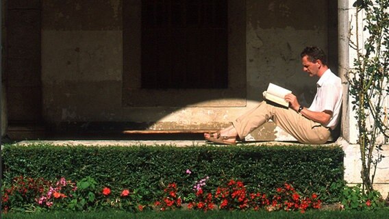 Lesender Mann in einem Klostergarten © dpa Foto: Pascal Deloche