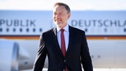 Finanzminister Christian Lindner steht auf dem Flughafen Berlin Brandenburg vor einem Regierungsflugzeug. © Bildfunk Foto: Bernd von Jutrczenka/dpa