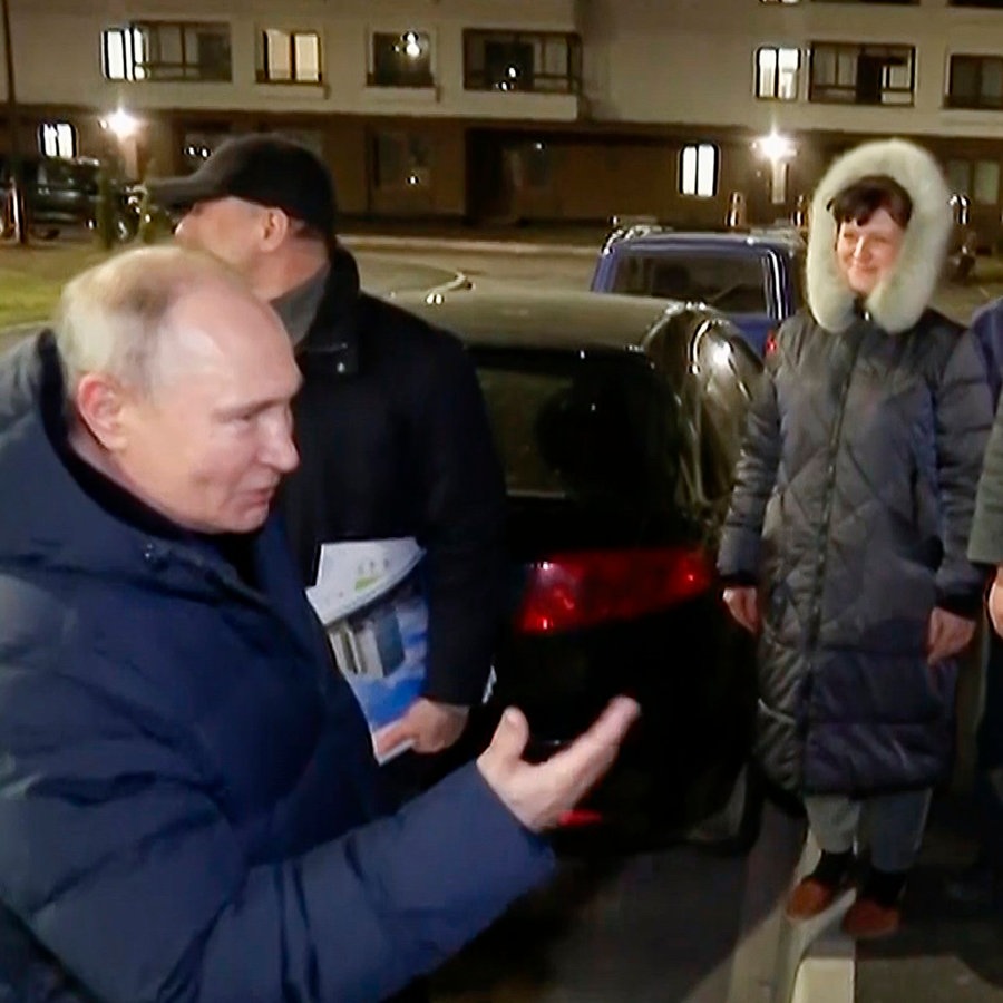 Putin spricht im besetzten Mariupol mit Menschen auf der Straße. Es ist dunkel. © Russisches Fernsehen via AP/dpa 