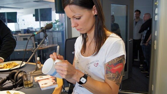 Popsängerin Christina Stürmer signiert einen NDR 1 Welle Nord Becher. © NDR Foto: Alexandra Hilscher