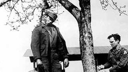 Desertierter Soldat hängt an einem gerade knospenden Baum. Zwei Amerikaner binden ihn los. (Bild: dpa)  