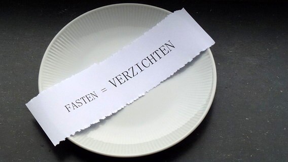 Auf einem leeren Teller liegt ein Zettel mit der Aufschrift fasten = verzichten © NDR Foto: Axel Franz
