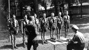 Mitglieder der Hitler-Jugend stehen in einer Reihe vor ihrem Vorgesetzten. © picture-alliance / dpa Foto: dpa