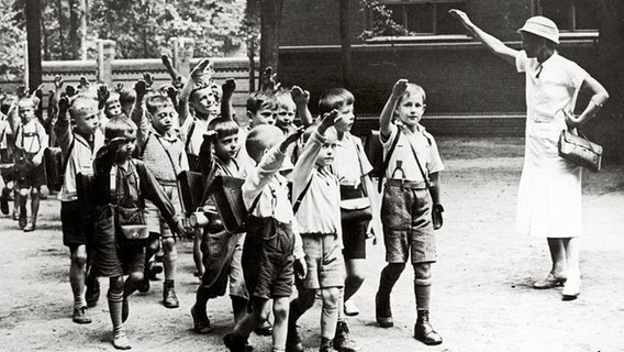 Eine Lehrerin verabschiedet ihre Schulkinder mit dem Hitler-Gruß. © picture-alliance / IMAGNO/Austri Foto: Anonym