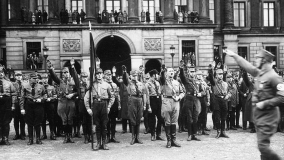 Männer der SA und Adolf Hitler stehen 1933 vor dem Braunschweiger Residenzschloss und erheben den Arm zum Hitler-Gruß. © picture-alliance / akg-images Foto: akg-images