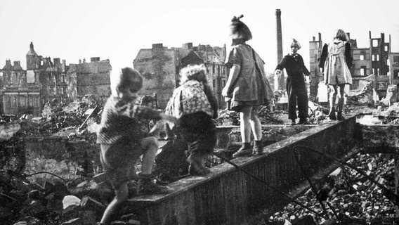 Kinder spielen in der Nachkriegszeit in den Trummern und stehen auf einer Mauerkante. © picture-alliance  dpa Foto: picture-alliance  dpa
