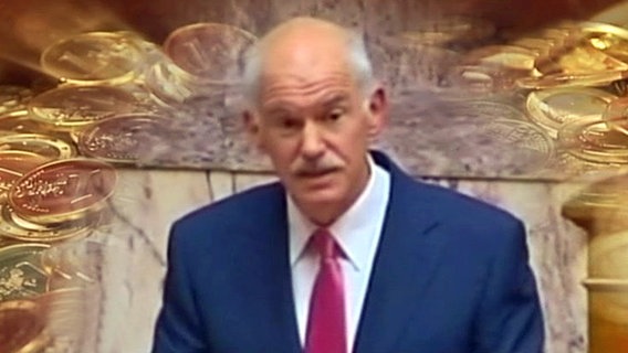 Papandreou. Im Hintergrund goldene Münzen. © NDR 