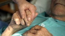 Eine Hand hält die Hand einer älteren Frau. © picture-alliance Foto: Lehtikuva Sari Gustafsson