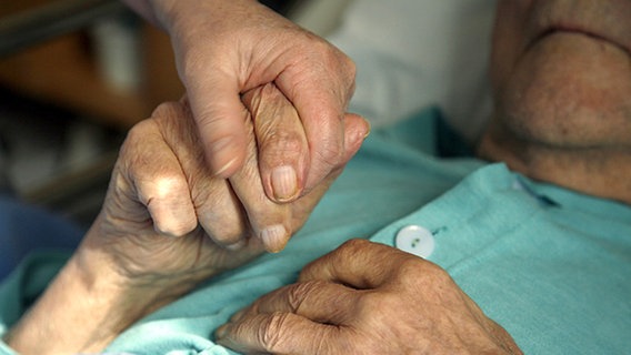Eine Hand hält die Hand einer älteren Frau. © picture-alliance Foto: Lehtikuva Sari Gustafsson