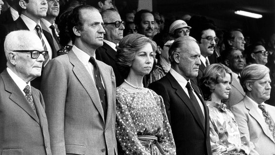 Bundeskanzler Helmut Schmidt steht mit dem spanischen Königspaar Juan Carlos und Sofia im Stadion Santiago Bernabeu bei der Fußball-WM 1982 beim Spiel Italien gegen Deutschland © picture alliance 