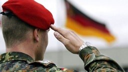 Soldat salutiert vor deutscher Fahne © picture-alliance / dpa 