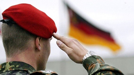 Soldat salutiert vor deutscher Fahne © picture-alliance / dpa 