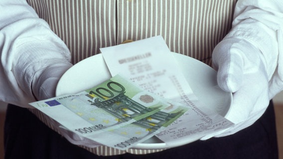 Kellner hält Teller mit Rechnung und Bargeld © picture-alliance/chromorange 