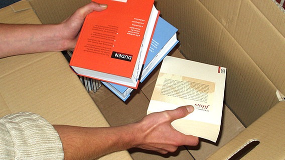 Bücher werden in einen Umzugskarton gepackt. © NDR 