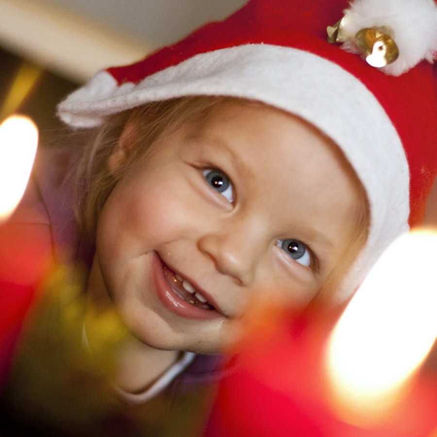 Ein kleines Kind mit Weihnachtsmütze sitzt vor einem Adventkranz mit brennenden Kerzen. © picture alliance / EXPA /APA/ picturedesk.com Foto: EXPA