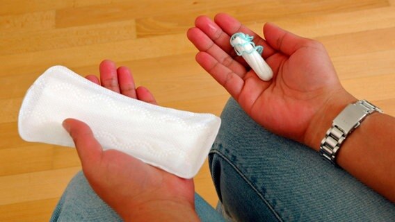 Eine Frau hält eine Binde und einen Tampon in den Händen. © picture alliance / IMAGEBroker 