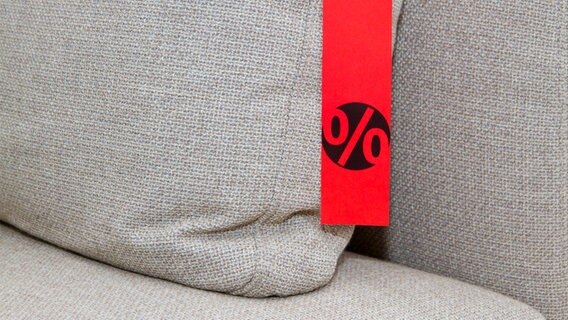 Ein Angebotsschild mit einem Prozent-Zeichen hängt auf einem Sofa. © fotolia.com Foto: Jürgen Fälchle