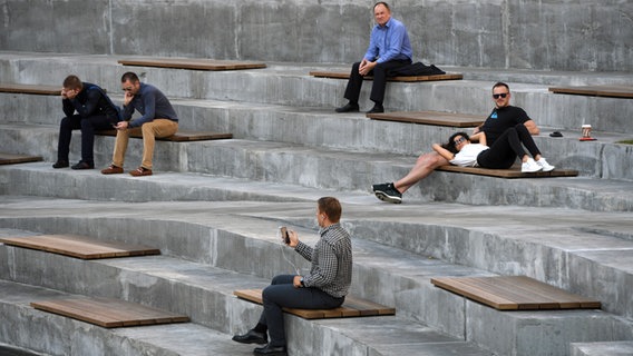 Menschen sitzen auf Holzbänken in einem Amphitheater. © dpa 