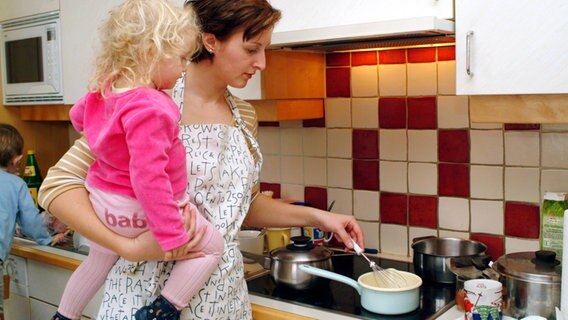 Eine Mutter mit Kind bei dem Kochen in der eigenen Küche. © Imago Foto: imagebroker / begsteiger