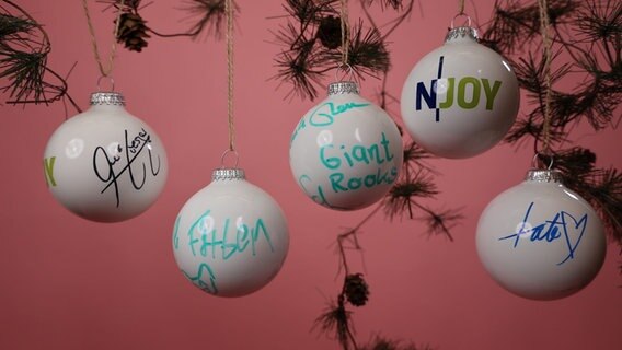 Von Stars signierte N-JOY Weihnachtskugeln vor einem rosa Hintergrund. © NDR/N-JOY Foto: NDR/N-JOY