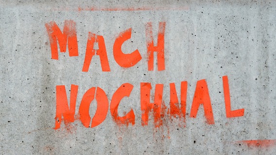 "Mach nochmal" steht auf einer Wand in orangener Neonfarbe. © Photocase Foto: Soer Alex