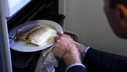 Ein Mann holt Lasagne aus einem Ofen  