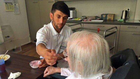 Nazim hilft einer älteren Dame beim Essen  Foto: Bettina Less