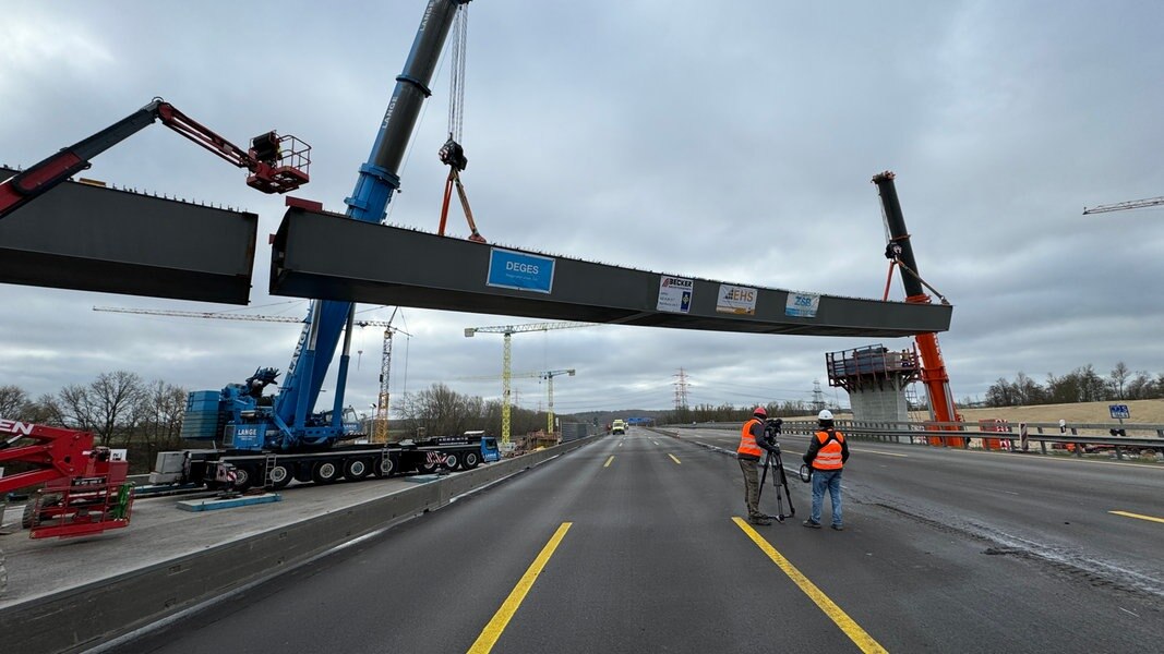 Eine Brücke wird über die Autobahn 7 mit einem Kran transportiert.