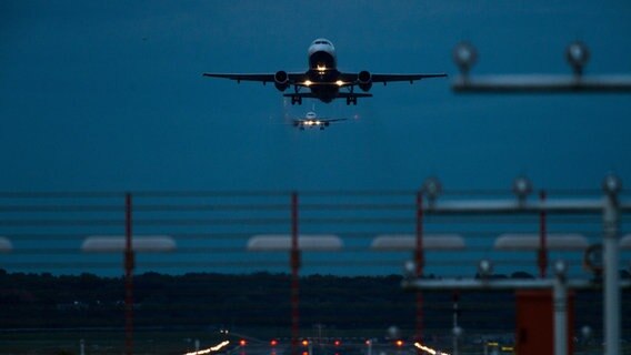 Ein Flugzeug startet im Dunkeln vom Hamburger Flughafen. © picture alliance / Christophe Gateau/dpa | Christophe Gateau 