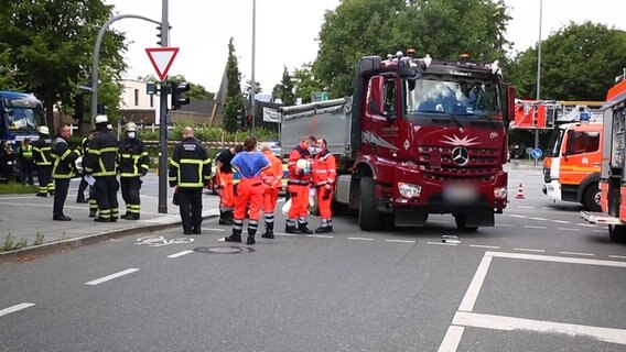 Feuerwehrleute und Sanitäter stehen neben LKW an einem Unfallort auf abgesperrter Straße in Poppenbüttel © NonstopNews 