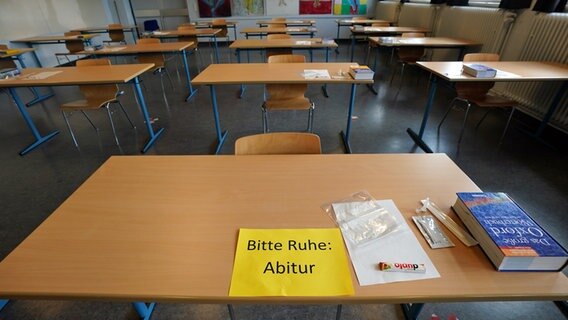 Ein Zettel mit der Aufschrift "Bitte Ruhe: Abitur" liegt neben einem Corona-Schnelltest, einen Schokoladenriegel und einem Englisch-Wörterbuch auf einem Tisch in einer Hamburger Schule. © picture alliance/dpa Foto: Marcus Brandt