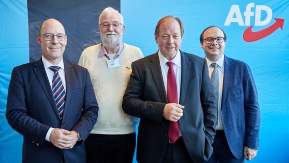 Dirk Nockemann (3.v.l.), Landesvorsitzender der AfD Hamburg, sowie die Stellvertretenden Landesvorsitzenden Alexander Wolf, Joachim Körner und Krzysztof Walczak (v.l.n.r.) stehen im Bürgersaal Wandsbek während eines AfD-Landesparteitags vor einer blauen Wand mit dem Logo der AfD. © picture alliance / dpa Foto: Georg Wendt