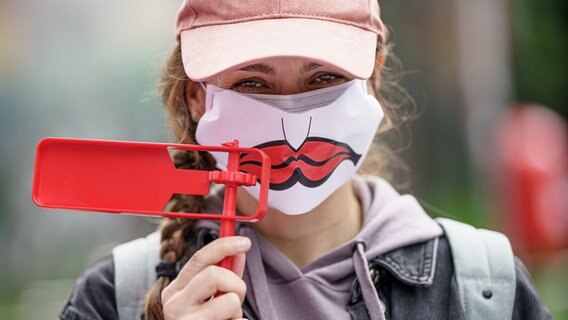 Eine Frau protestiert bei einer Kundgebung gegen einen geplanten Stellenabbau bei Aida Cruises mit einer roten Ratsche in der Hand. © picture alliance/dpa | Axel Heimken Foto: Axel Heimken