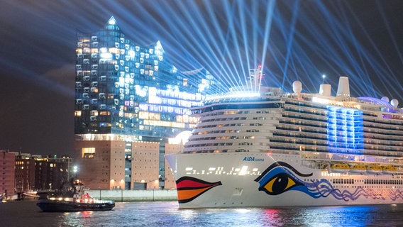 Das Kreuzfahrtschiff "AIDAcosma" fährt am Abend nach einer Taufzeremonie bunt illuminiert durch den Hafen mit der Elbphilharmonie. © picture alliance/dpa | Daniel Bockwoldt Foto: Daniel Bockwoldt