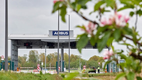 Hinter Zweigen mit Apfelblüten ist das Südtor zum Werksgelände von Airbus in Finkenwerder zu sehen. © picture alliance/dpa Foto: Georg Wendt