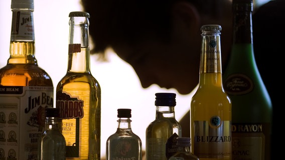 Ein Jugendlicher sitzt hinter Flaschen mit Alkohol © Picture Alliance Foto: Jens Büttner
