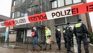 Polizeibeamte stehen vor dem Gebäude der Zeugen Jehovas im Stadtteil Alsterdorf. © dpa Foto: Markus Scholz