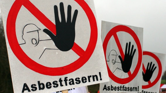 Mehrere Schilder mit der Aufschrift "Asbestfasern" warnen vor Asbest. © Daniel Bockwoldt/dpa Foto: dpa