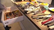 Auf einer Küchenarbeitsplatte liegen ganz viele Kochlöffel, Kochzangen und Wender. © NDR Foto: NDR