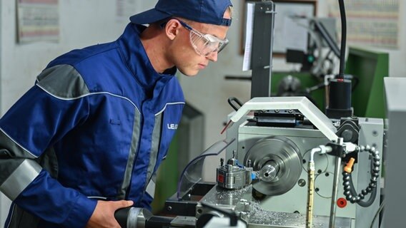 Ein Auszubildender zum Mechatroniker arbeitet an einer Drehmaschine. © dpa Foto: Patrick Pleul