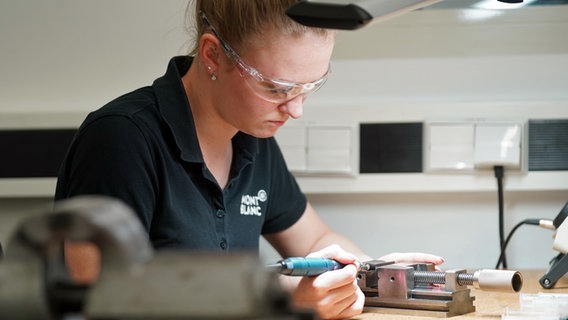 Eine Auszubildende zur Werkzeugmechanikerin poliert eine Feder in der Werkstatt des Schreibgeräteherstellers Montblanc in Hamburg. © picture alliaqnce / dpa Foto: Marcus Brandt