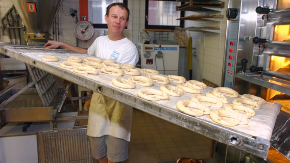 Ein Bäcker schiebt ein Blech mit Brezeln in einen Ofen. © picture alliance / SvenSimon | SVEN SIMON Foto: SvenSimon